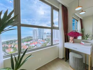 Una habitación con una ventana grande, un escritorio y una planta. en The Sóng Apartment Vũng Tàu, en Vung Tau