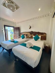 ルアンパバーンにあるAlana Luang Prabangのベッドルーム1室(ベッド3台、青と白のシーツ付)