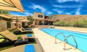 een buitenzwembad met stoelen en een huis bij Ferienhaus Für 12 Personen In Chania, Kreta West Kreta in Georgioupolis