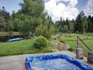 un bain à remous installé sur une terrasse à côté d'un champ dans l'établissement Gîte chaleureux avec spa, cheminée et terrasse au coeur de la nature - FR-1-496-340, à Saint-Genest-Malifaux
