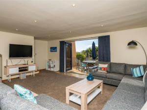a living room with a couch and a tv at La Belle Maison - Ruakaka Holiday Apartment in Ruakaka