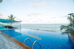 a swimming pool with the ocean in the background at Palado Hotel Mui Ne in Ấp Thiện Phước