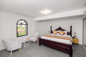 a bedroom with a bed and two chairs and a window at Palado Hotel Mui Ne in Ấp Thiện Phước