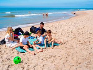 a group of people sitting on the beach at 4 person holiday home in Ringkøbing-By Traum in Ringkøbing