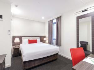 um quarto com uma cama, uma escrivaninha e uma cadeira vermelha em ibis Styles Kingsgate Hotel em Melbourne mais 47 fotografias