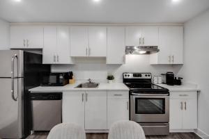 a kitchen with white cabinets and stainless steel appliances at Modern 2Bed Suite Near Capilano Bridge & Trails in North Vancouver