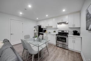 a kitchen with white cabinets and a glass table at Modern 2Bed Suite Near Capilano Bridge & Trails in North Vancouver