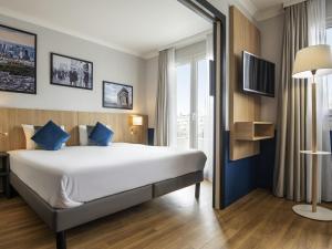 a hotel room with a large bed with blue pillows at Aparthotel Adagio La Défense Kléber in Courbevoie