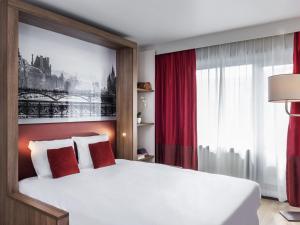 a bedroom with a large white bed with red pillows at Aparthotel Adagio Paris Bercy Village in Paris