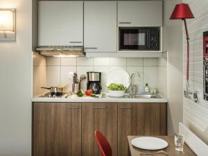 a kitchen with white cabinets and a red lamp at Aparthotel Adagio Paris Bercy Village in Paris