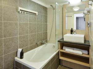 een badkamer met een bad, een wastafel en een spiegel bij Aparthotel Adagio Monaco Monte Cristo in Beausoleil