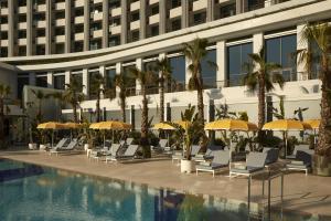 a hotel swimming pool with chairs and umbrellas at Conrad Athens The Ilisian in Athens