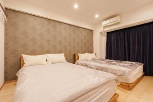 a bedroom with two beds and a wall with a window at 青葉邸 AOZORA 1002 Near Dotonbori 3LDK 2 Bath 2 WC Premium Tower Residence in Osaka