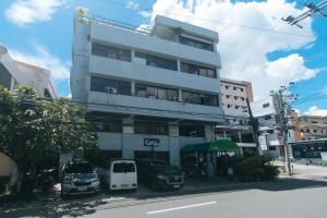 a tall white building with cars parked in front of it at RedDoorz @ Junquera Extension Cebu in Cebu City