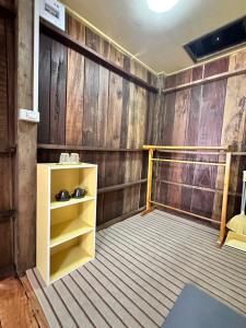 une pièce aux murs en bois et une étagère jaune dans l'établissement Moonshine Phayam beach resort & restaurant, à Ranong