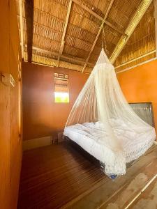 a bed in a room with a mosquito net at THE Drift Wood House in Besir