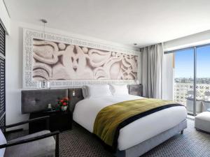 ラバトにあるソフィテル ラバト ジャルダン デ ローズの大きなベッドと大きな窓のある寝室