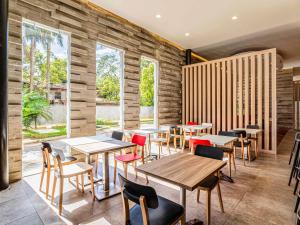 a restaurant with wooden tables and chairs and windows at Ibis Merida in Mérida +57 photos