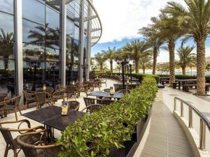 a restaurant with tables and chairs and palm trees at Ibis Abu Dhabi Gate in Abu Dhabi