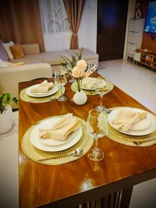 Una mesa de madera con platos y copas de vino encima. en Kahlua, en Sampong