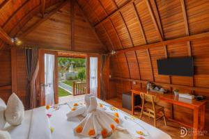 Cette chambre comprend un lit, une télévision et une table. dans l'établissement Bunut Bungalow, à Nusa Penida