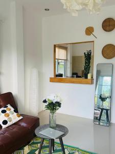 ein Wohnzimmer mit einem Sofa und einer Vase mit Blumen auf dem Tisch in der Unterkunft Cozy Villa in the Tropical Garden in Ko Phangan