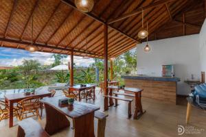 une salle à manger avec des tables et des chaises en bois dans l'établissement Bunut Bungalow, à Nusa Penida