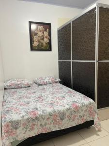 马瑙斯Ana Claudia的卧室里有一张铺着花卉床罩的床