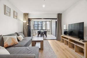 ein Wohnzimmer mit Couch und Flachbildfernseher in der Unterkunft Bright 1BR Apartment in the heart of Dickson in Downer