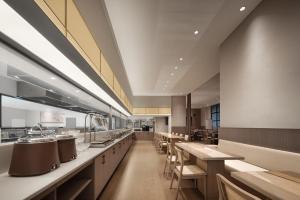 重慶市にあるWalling Hotel - Chongqing hongyadong jialingjiang binjiangluの長いカウンターとテーブルのある広いキッチン