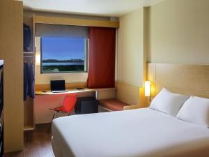 a bedroom with a bed and a desk with a laptop at Ibis Cancun Centro in Cancún