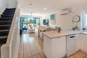 a kitchen and living room with a dining room and stairs at Sunset Waters 12 on Hamilton Island by HamoRent in Hamilton Island