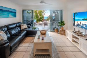 a living room with a black leather couch and a table at Sunset Waters 12 on Hamilton Island by HamoRent in Hamilton Island