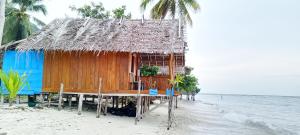 a hut on a beach with the water at Nyanderos homestay in Poelau Mansoear