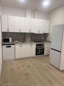 a kitchen with white cabinets and a refrigerator at Cal Sereno in Agramunt