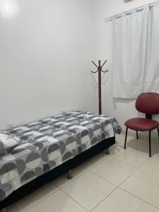 ein Schlafzimmer mit einem Bett und einem roten Stuhl in der Unterkunft Fênix in Manaus