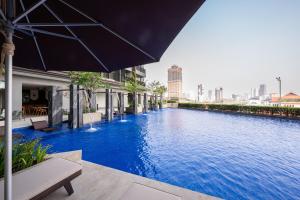 金边Comfy Apartment-Perfect City Stay at TK Area的建筑物旁边有带遮阳伞的游泳池