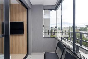 Zimmer mit Balkon und Flachbild-TV in der Unterkunft Edifício Smart Home | Gonzaga Stays in Curitiba