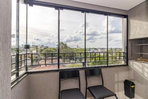 2 Stühle vor einem Fenster mit Aussicht in der Unterkunft Edifício Smart Home | Gonzaga Stays in Curitiba