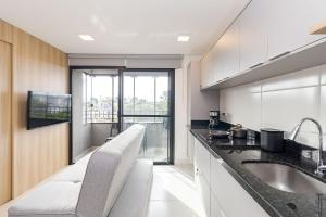 eine Küche mit einem Waschbecken und einem großen Fenster in der Unterkunft Edifício Smart Home | Gonzaga Stays in Curitiba
