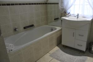 a bathroom with a bath tub and a sink at 3 Liebeloft Guest House in Edenvale