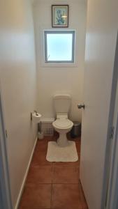 Un pequeño baño con inodoro y ventana. en Scenic Coastal Gem with Pool, Tennis, Securely Gated, en Whangaparaoa