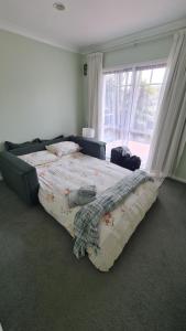 Una cama grande en un dormitorio con ventana. en Scenic Coastal Gem with Pool, Tennis, Securely Gated, en Whangaparaoa
