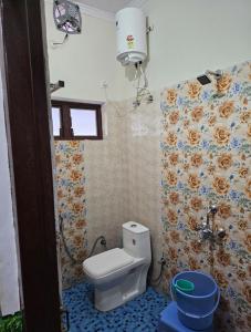 a bathroom with a toilet and a flower patterned wall at Hotel Dream House in Kanatal
