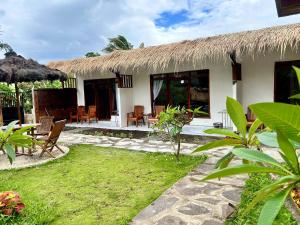 テテバトゥにあるZiraya Villa & Bungalowの椅子とテーブルと藁葺き屋根のある家