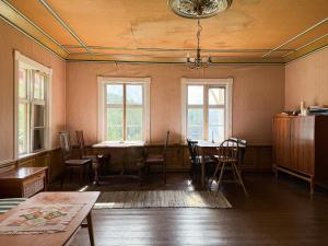 a room with a table and chairs and windows at Gård Fra 1770 Med Flydende Sauna Ved Søen in Hennseid