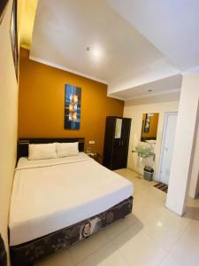 - une chambre avec un grand lit et un mur jaune dans l'établissement Hommy Inn Timoho, à Demangan