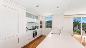 a kitchen with white cabinets and a white counter top at The Pavillion 1 - Beachfront in Wamberal
