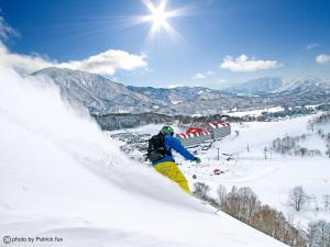 a person is skiing down a snow covered slope at Hotel Green Plaza Hakuba in Otari
