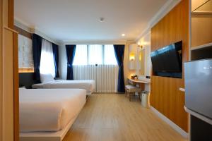a hotel room with two beds and a television at Sira Boutique Chiang Mai in Chiang Mai